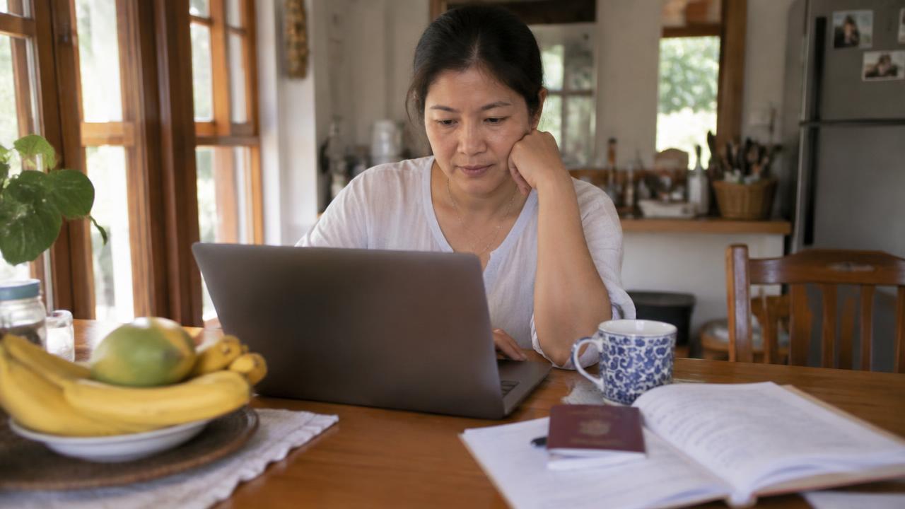 Woman reading answers on a laptop beside a passport (illustrative photo, not a real client)